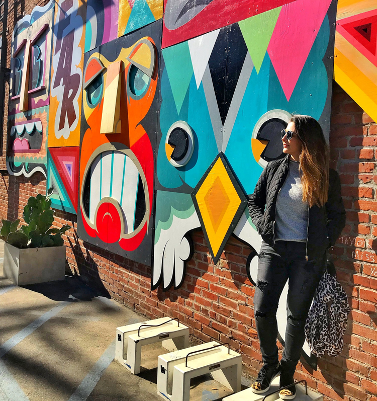 Mari Sebrian standing in front of a colorful geometric mural